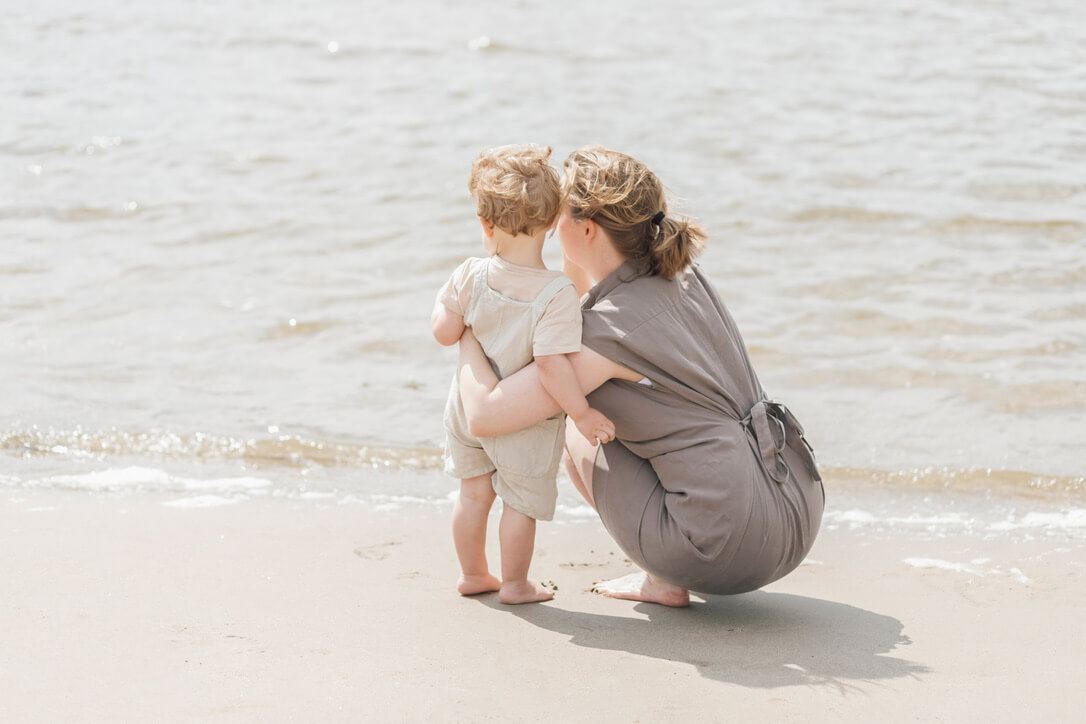 Slaapcoach mama en kindje op het strand in Nijmegen, baby- en kinderslaapcoaching in de regio Slaapcoach mama en kindje op het strand kijken naar het water in Nijmegen, baby- en kinderslaapcoaching in de regio